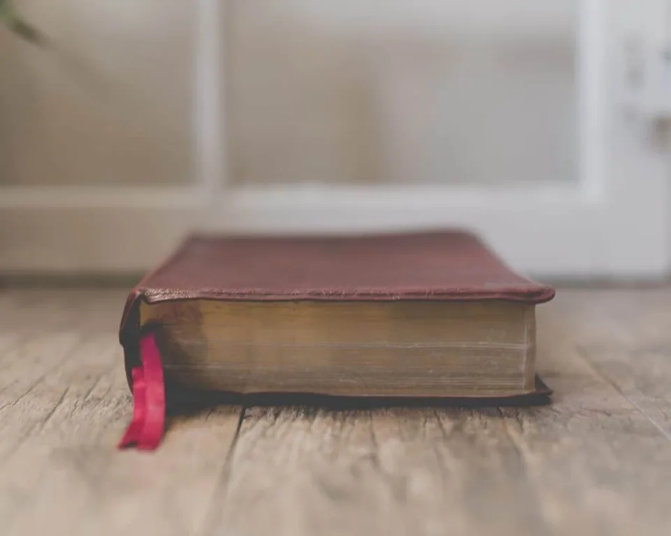 Closed brown leather bible sitting on an old wooden floor
