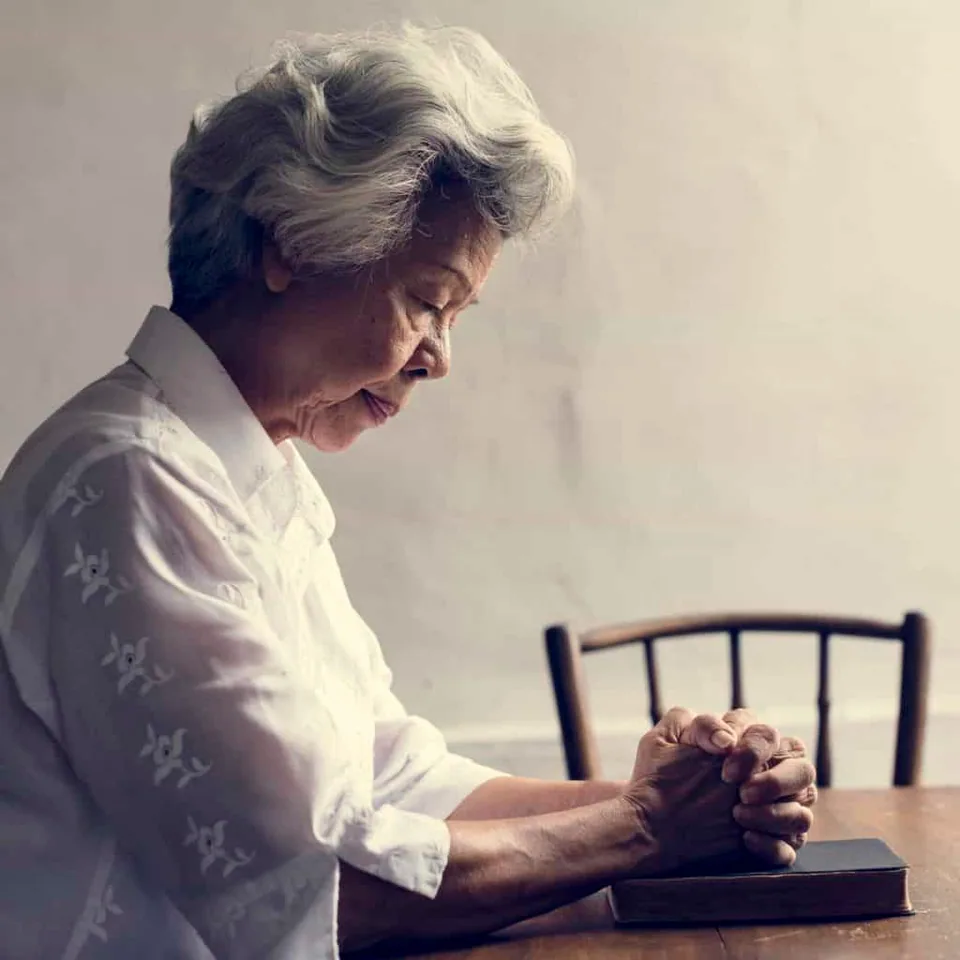 An elderly lady praying