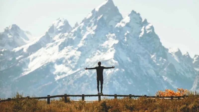 Man raising hands looking at a mountain