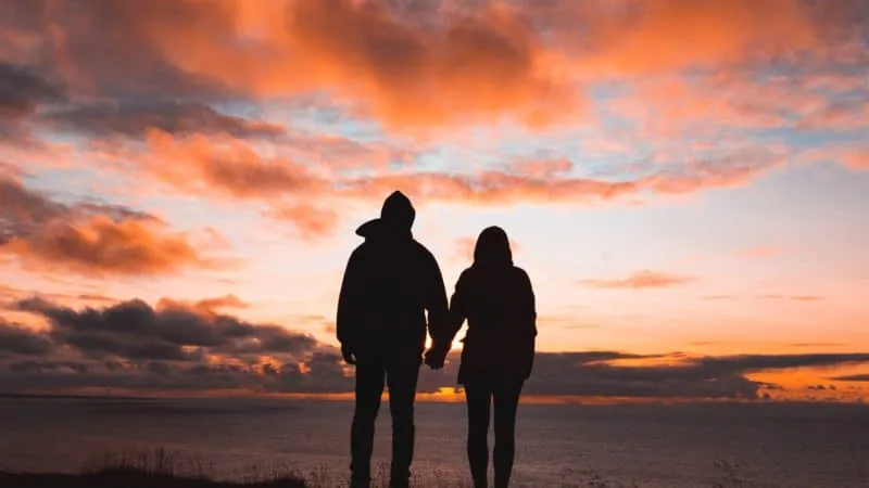 A man and a woman holding hands on a beautiful sunset