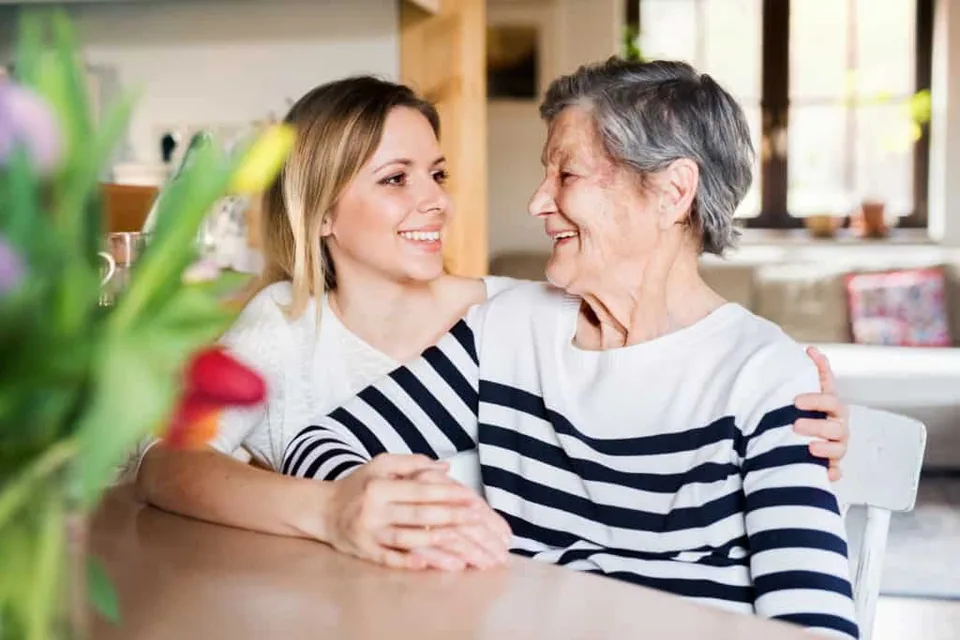 A grand daughter and grandmother smiling at each other