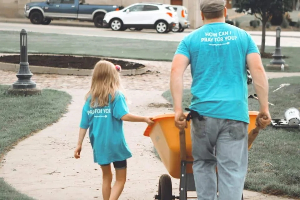 Father Pushing a wheel barrow with his daughter next to him