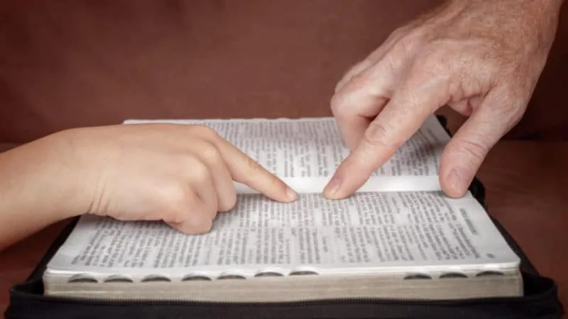 Fingers pointing at the Bible